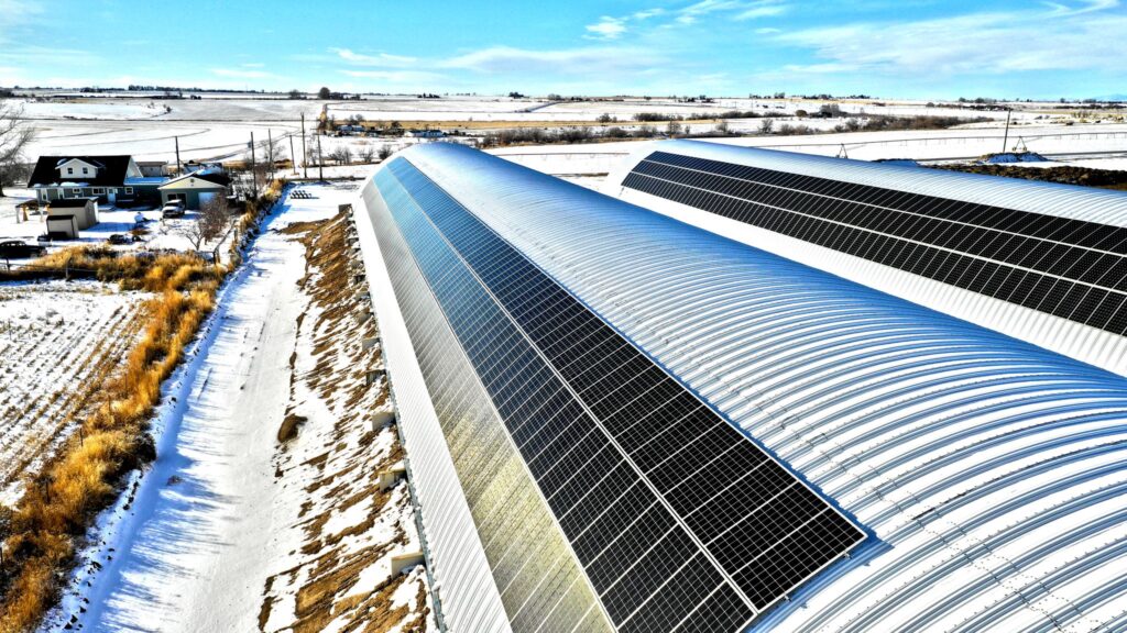 Poultry barns in Idaho during the winter with large stretches of solar panels installed on the roofs. 